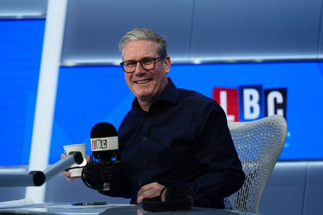 Sir Keir Starmer holding a cup of coffee while sitting at a microphone in an LBC radio studio