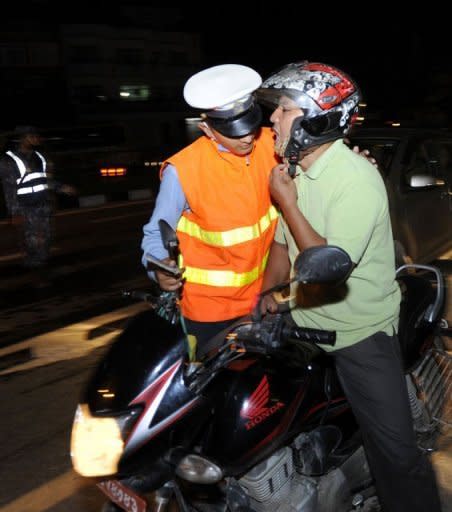 A Nepalese traffic policeman (L), seen leaning over to smell the breath of a motorcyclist to determine the level of his alcohol consumption at a roadblock in Kathmandu. With breathalysers scarce and blood tests unavailable, the method for catching lawbreakers in Kathmandu is primitive as police officers simply stop drivers and engage them in conversation