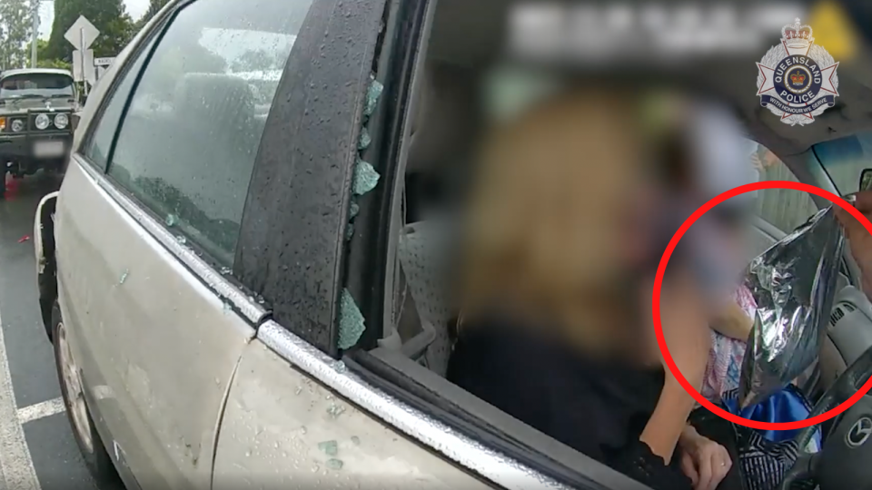 A still image from the Queensland Police video showing the Sunshine Coast woman appearing to hand a police officer a bag from a cask wine box.