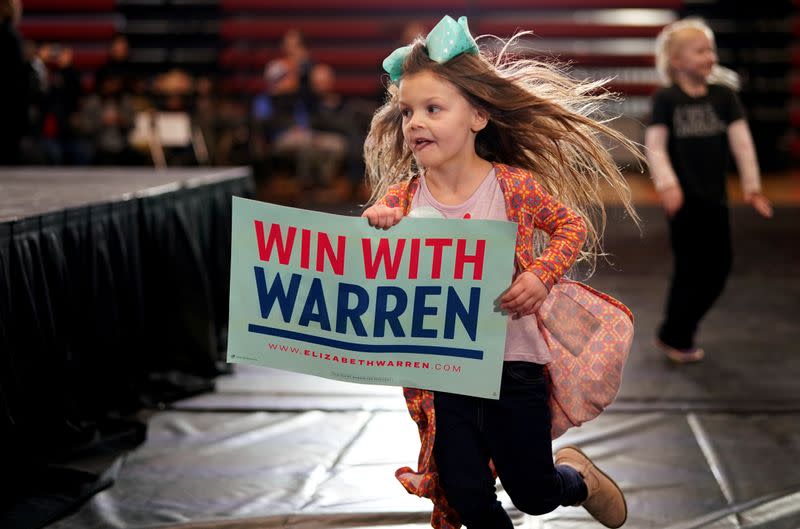 Emma Patty runs with a sign supporting Democratic 2020 U.S. presidential candidate and U.S. Senator Elizabeth Warren (D-MA) before a campaign event in Cedar Rapids