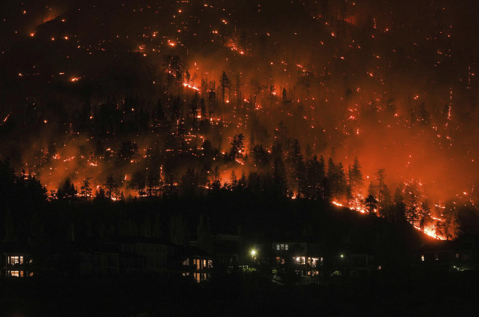 The McDougall Creek wildfire burns on the mountainside above houses in West Kelowna, B.C., on Friday, Aug. 18, 2023. Thousands have fled, driving hundreds of kilometers (miles) to safety or waiting in long lines for emergency flights, as the worst fire season on record in Canada showed no signs of easing. (Darryl Dyck/The Canadian Press via AP)