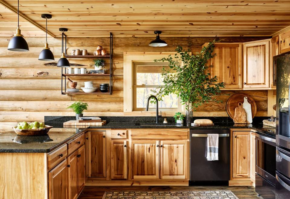 a pine wood kitchen with black appliances and countertops and lighting