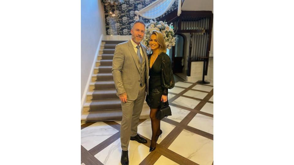 Ola Jordan in a mini dress with James Jordan in front of a staircase