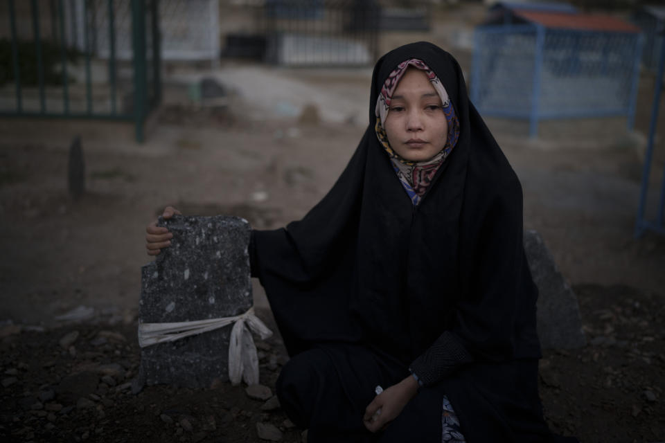 Basima Hidari, 20, sits on the grave of her brother Ali Hidari in Kabul, Afghanistan, Thursday, Sept. 16, 2021. Hidari was injured and her 19-years-old brother Ali Hidari was killed last month when they were trying to enter the airport during the U.S.-led evacuation. (AP Photo/Felipe Dana)