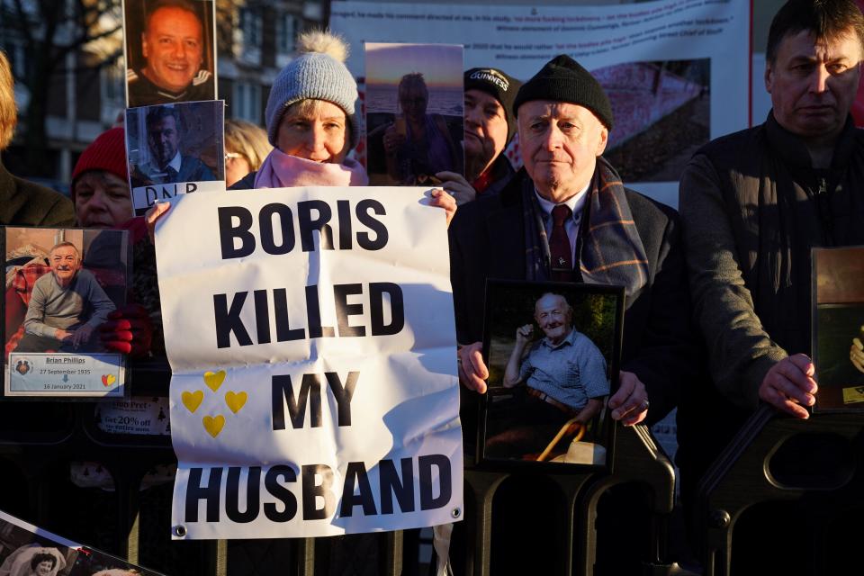 Protesters hold pictures and banners as they wait outside the UK COVID-19 Inquiry, where the former British Prime Minister Boris Johnson is giving evidence in London on Wednesday (REUTERS)