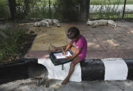 A child practices writing during a sidewalk class taught by an Indian couple, Veena Gupta and her husband Virendra Gupta, in New Delhi, India, on Sept. 3, 2020. It all began when Veena's maid complained that with schools shut, children in her impoverished community were running amok and wasting time. The street-side classes have grown as dozens of children showed keen interest. Now the Guptas, with help from their driver, teach three different groups three times a week, morning and evening. While many private schools switched to digital learning and online classes, children in most government-run schools either don’t have that option or don’t have the means to purchase digital learning tools like laptops and smartphones. (AP Photo/Manish Swarup)