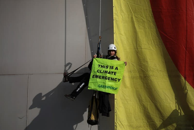 A Greenpeace activist hangs from an oil tank at the Hellenic Petroleum refineries in Aspropyrgos near Athens