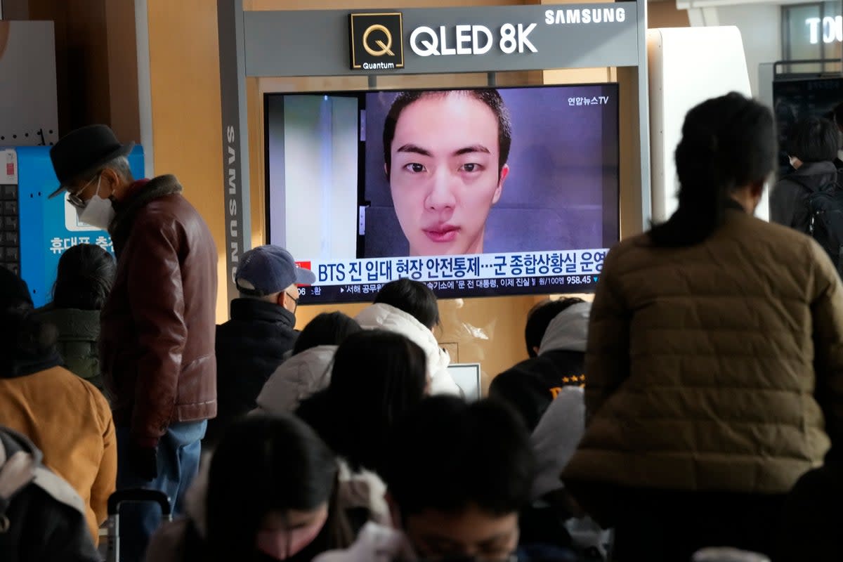 A TV screen shows an image of BTS's member Jin with buzz cut, at the Seoul Railway Station in Seoul, South Korea, Monday, 12 December 2022 (Associated Press)