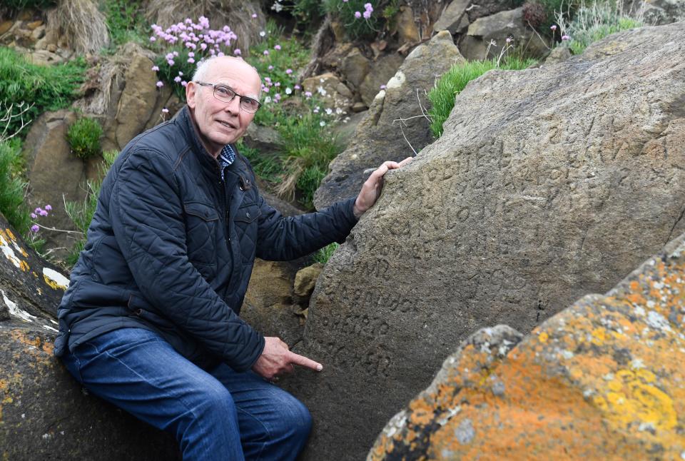 French local councillor in charge of small heritage Michel Paugam poses on May 7, 2019 as he shows inscriptions composing indecipherable words on a rock in the Brittany village of Plougastel-Daoulas. (Photo by FRED TANNEAU/AFP/Getty Images)