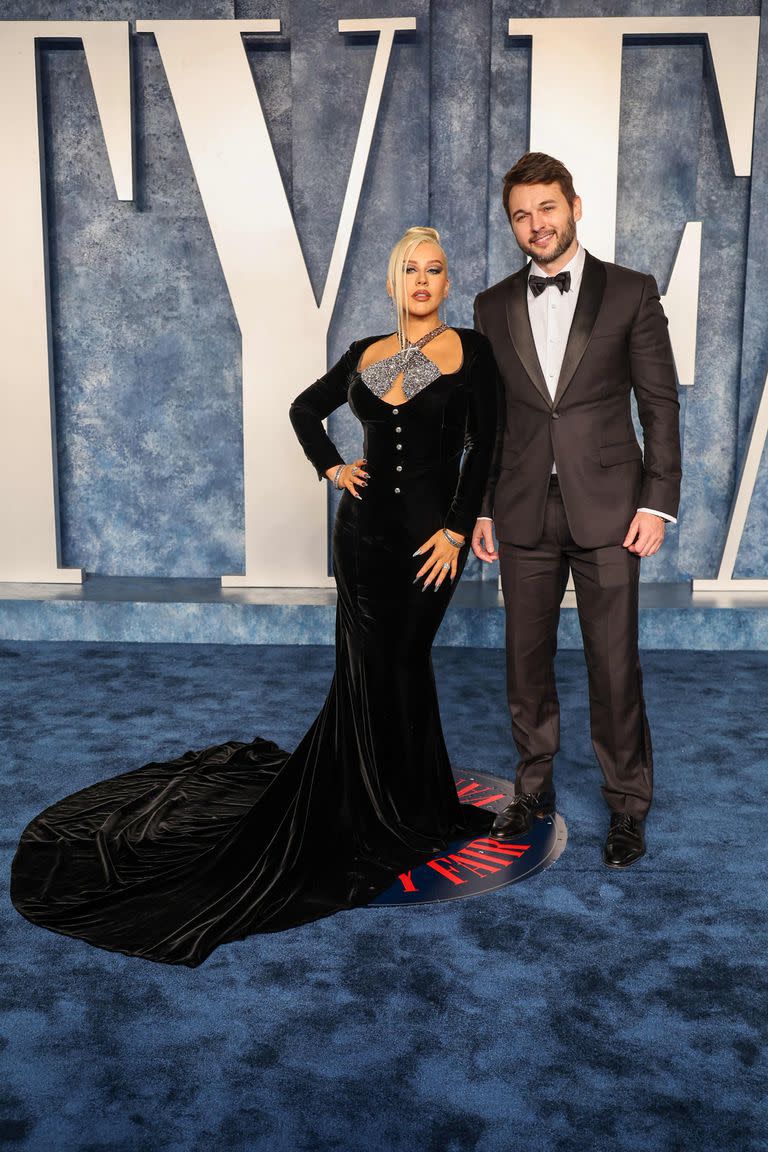 Christina Aguilera completó su falda negra con una pieza superior plateada y posó acompañada por el elegante Matthew Rutler