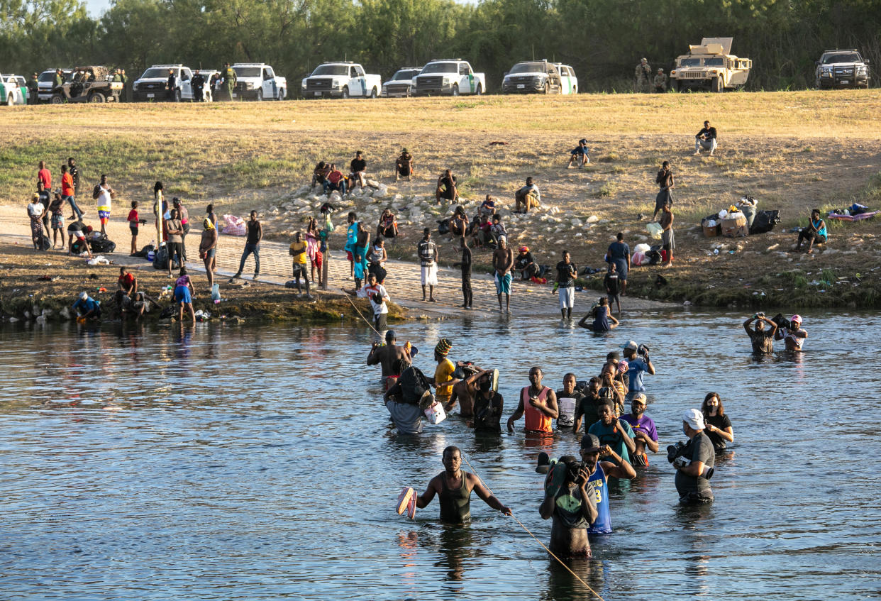 U.S. Border Patrol agents watch from their vehicles as migrants cross from a camp in Del Rio, Texas to go get food supplies on September 22, 2021 as seen from Ciudad Acuna, Mexico. U.S. immigration authorities have been deporting planeloads of migrants directly to Haiti, and others are reportedly being released into the United States to follow their asylum claims.  (John Moore/Getty Images)