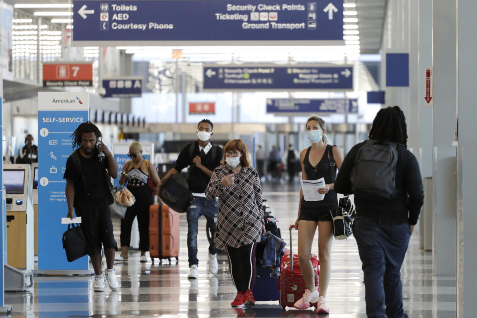 FILE - In this Tuesday, June 16, 2020, file photo, travelers walk through Terminal 3 at O'Hare International Airport in Chicago. In a report, Thursday, July 2, 2020, the government is recommending that travelers wear face coverings during air travel and says airlines should consider limiting capacity on planes to promote social distancing. But it stopped short of making new requirements. (AP Photo/Nam Y. Huh, File)