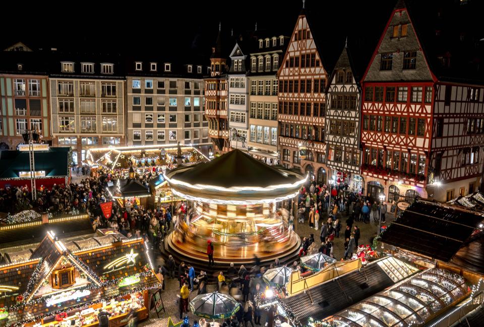 FILE - Lights illuminate the traditional Christmas Market with a merry-go-round, in Frankfurt, Germany, Monday, Nov. 21, 2022. In cities across Europe, officials are wrestling with a choice this Christmas. Dim lighting plans to send a message of energy conservation and solidarity with citizens squeezed by both higher energy costs and inflation or let the lights blaze in a message of defiance after two years of pandemic-suppressed Christmas seasons, creating a mood that retailers hope loosen holiday purses. (AP Photo/Michael Probst, File)