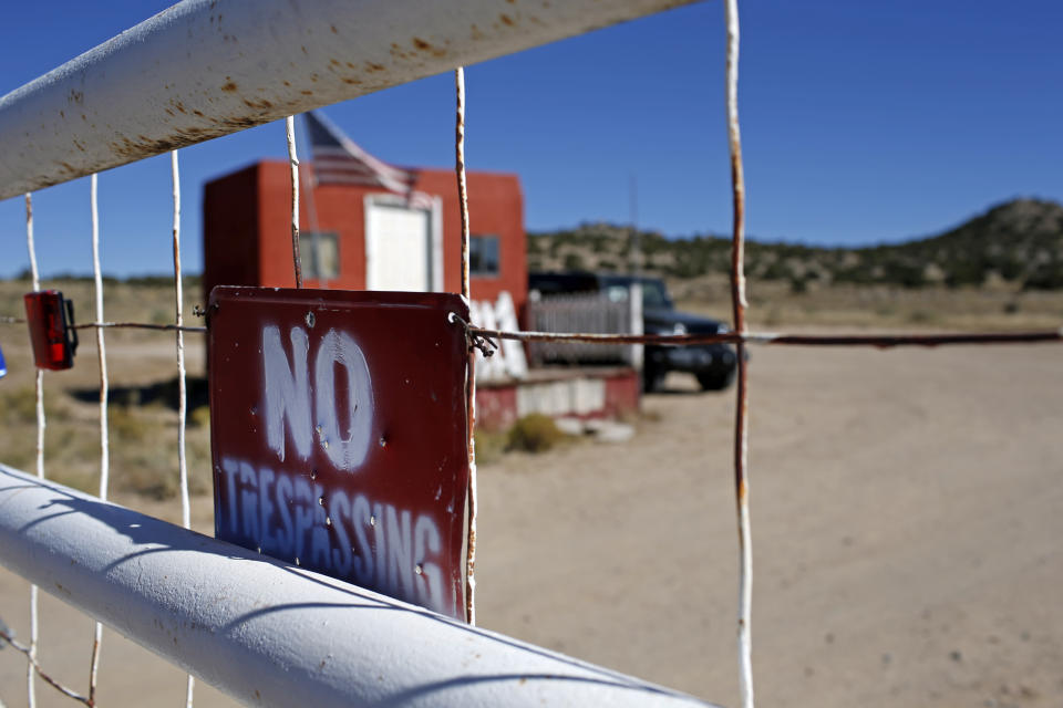 A "No Trespassing" sign hangs on the fence at the entrance to the Bonanza Creek Ranch film set in Santa Fe, N.M., Wednesday, Oct. 27, 2021. New Mexico authorities said they have recovered a lead projectile believed to have been fired from the gun used in the fatal movie-set shooting. (AP Photo/Andres Leighton)