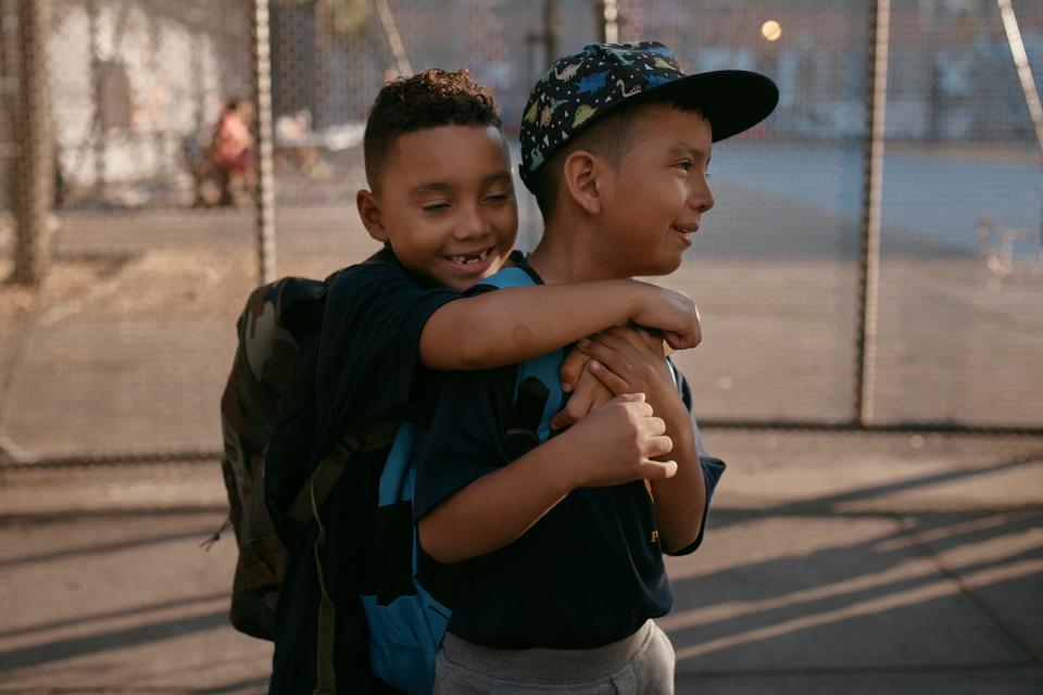 Damien Salinas, 5, right, hugs  a friend on his first day of school in New York City after his family emigrated from Ecuador in June. Damien and her family have been living in a room at the historic Roosevelt Hotel, which has been converted into a temporary shelter.