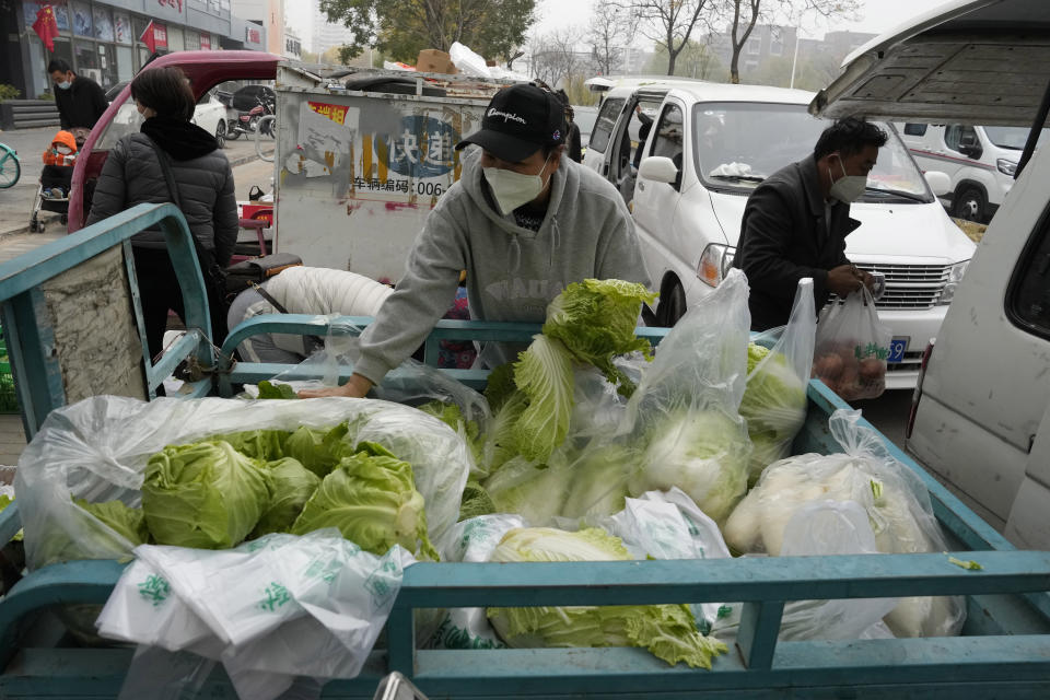 Residents buy fresh vegetables from street vendors as restaurants are closed in some districts in Beijing, Thursday, Nov. 24, 2022. China is expanding lockdowns, including in a central city where factory workers clashed this week with police, as its number of COVID-19 cases hit a daily record. (AP Photo/Ng Han Guan)