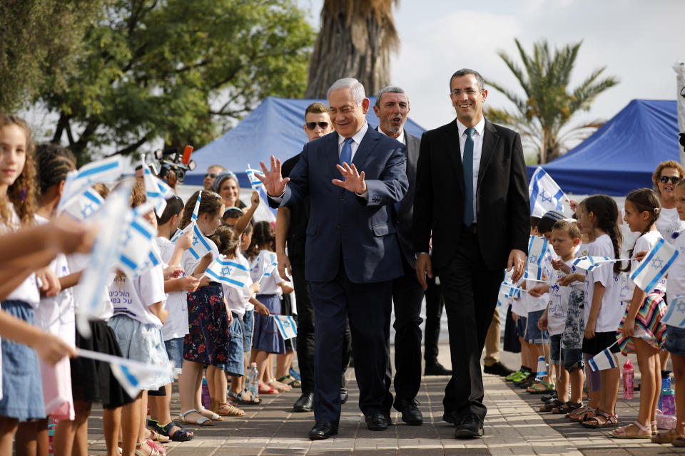 Israeli Prime Minister Benjamin Netanyahu, center left, walks with Education Minister Rafi Peretz as he greets students during a ceremony opening the school year in the settlement of Elkana Sunday, Sept. 1, 2019. Netanyahu is reaffirming his pledge to impose Israeli sovereignty on West Bank settlements. (Amir Cohen/Pool Photo via AP)