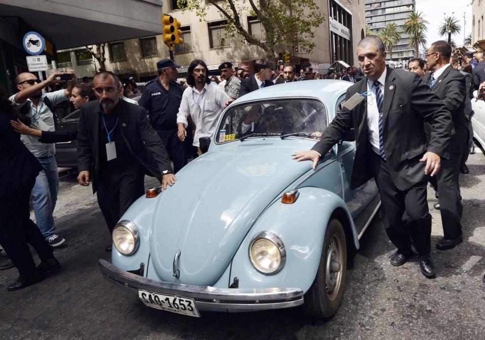 Security personnel surround the Volkswagen Beetle belonging to Jose Mujica as he is being driven away after handing over the presidential sash to Tabare Vazquez in Montevideo