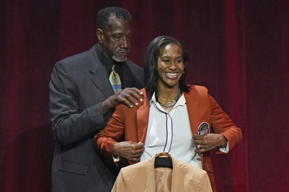 Harvey Catchings, left, helps daughter Tamika Catchings put on her Hall of Fame jacket at the 2020 Basketball Hall of Fame awards tip-off celebration and awards gala, Friday, May 14, 2021, in Uncasville, Conn. (AP Photo/Kathy Willens)