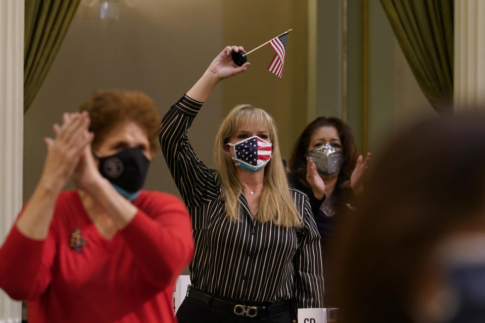 Jackie Cisneros, center, waves an American flag as she and other members of California's Electoral College celebrate the election of President-Elect John Biden as President in Sacramento, Calif., Monday, Dec. 14, 2020. (AP Photo/Rich Pedroncelli, Pool)