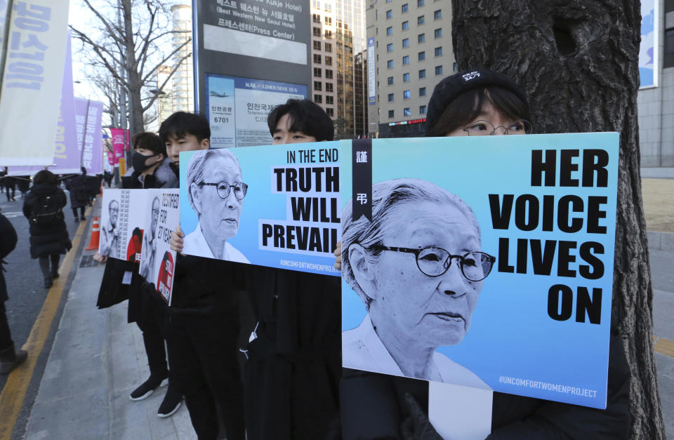 Mourners hold images of the deceased Kim Bok-dong, a former South Korean sex slave, during her funeral ceremony in Seoul, South Korea, Friday, Feb. 1, 2019. Hundreds of mourners gathered Friday near the Japanese Embassy for the funeral of Kim forced as a girl into a brothel and sexually enslaved by the Japanese military in WWII. (AP Photo/Ahn Young-joon)