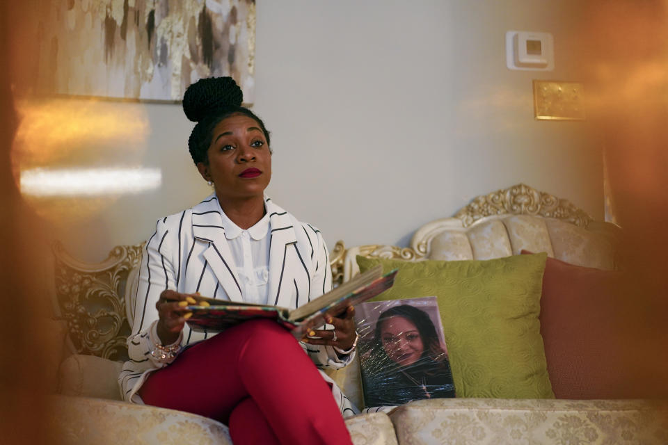 Nikiesha Thomas' sister Keeda Simpson pauses as she looks through family photos in her mother's, Nadine Thomas, home in Olney, Md., Thursday, Aug. 25, 2022. Next to her on the sofa is a photo of Nikiesha, who was shot and killed by her ex-boyfriend just days after filing for a protective order, last October. Victims of abuse and their families saw a quiet breakthrough this summer when the passage of a bipartisan gun safety bill in Congress included a proposal that would make it more difficult for intimate partners of convicted domestic abusers to obtain firearms. (AP Photo/Carolyn Kaster)