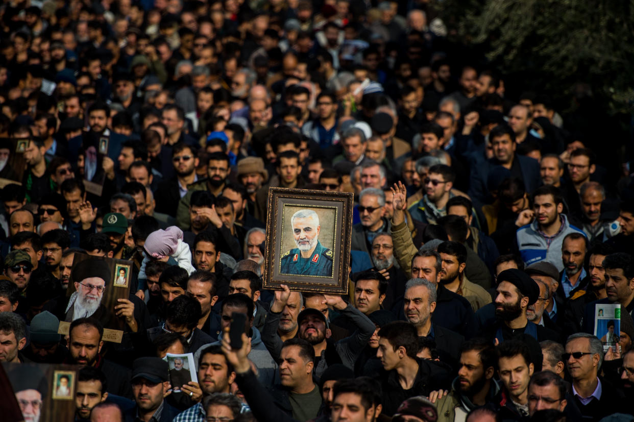 Protesters hold up an image of Qassem Soleimani.