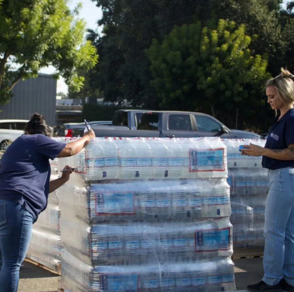 Rebecca Rosales (izquierda) y Savannah Silva, ambas de Self-Help Enterprises, etiquetan paquetes de agua embotellada el 19 de julio de 2023.