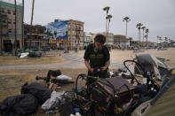 Jeremy Minney, a 43-year-old homeless man, sorts through his belongings in a homeless encampment set up along the boardwalk in the Venice neighborhood of Los Angeles, Tuesday, June 29, 2021. The proliferation of homeless encampments on Venice Beach has sparked an outcry from residents and created a political spat among Los Angeles leaders. (AP Photo/Jae C. Hong)