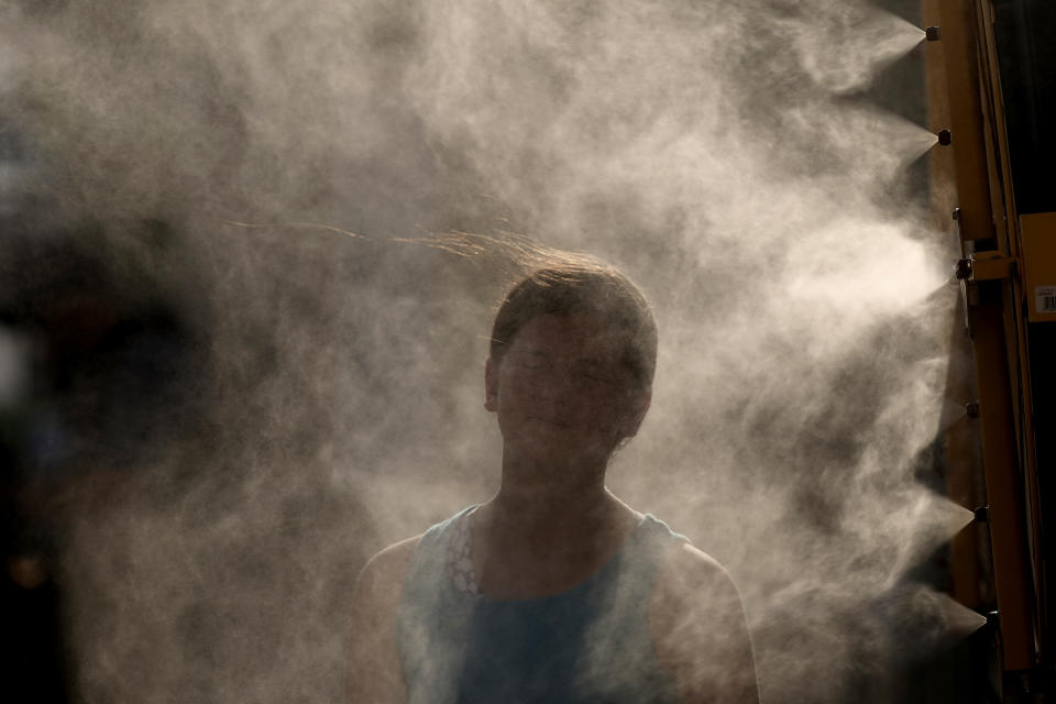 A woman cools off in a mister at Kauffman Stadium as temperatures approach 100 degrees fahrenheit before a baseball game between the Kansas City Royals and the Cleveland Guardians, Wednesday, June 28, 2023, in Kansas City, Mo. (AP Photo/Charlie Riedel)