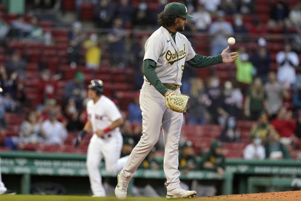 Oakland Athletics' Sean Manaea, right, gets a grip on the ball as Boston Red Sox's Hunter Renfroe, left, runs to home to score on a two-run home run by Bobby Dalbec in the second inning of a baseball game, Thursday, May 13, 2021, in Boston. (AP Photo/Steven Senne)