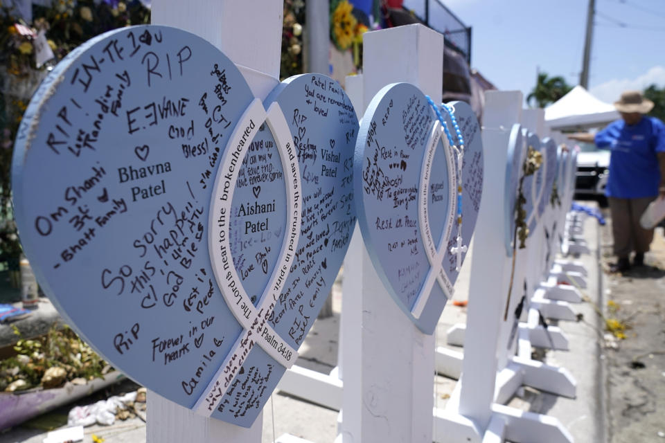 A wooden heart at a makeshift memorial remembers the family of Vishal and Bhavna Patel, who died along with their 1-year-old daughter Aishani, in the collapse of the nearby Champlain Towers South building, Wednesday, July 14, 2021, in Surfside, Fla. Removal and recovery work continues at the site of the partially collapsed condo building, Wednesday, in Surfside. (AP Photo/Lynne Sladky)