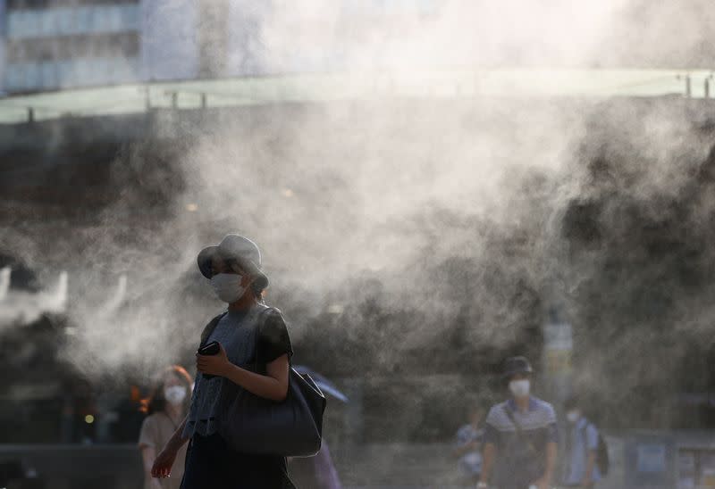 Passersby wearing protective face masks walk through a cooling mist during the Tokyo 2020 Olympic Games, amid the coronavirus disease (COVID-19) pandemic, in Tokyo