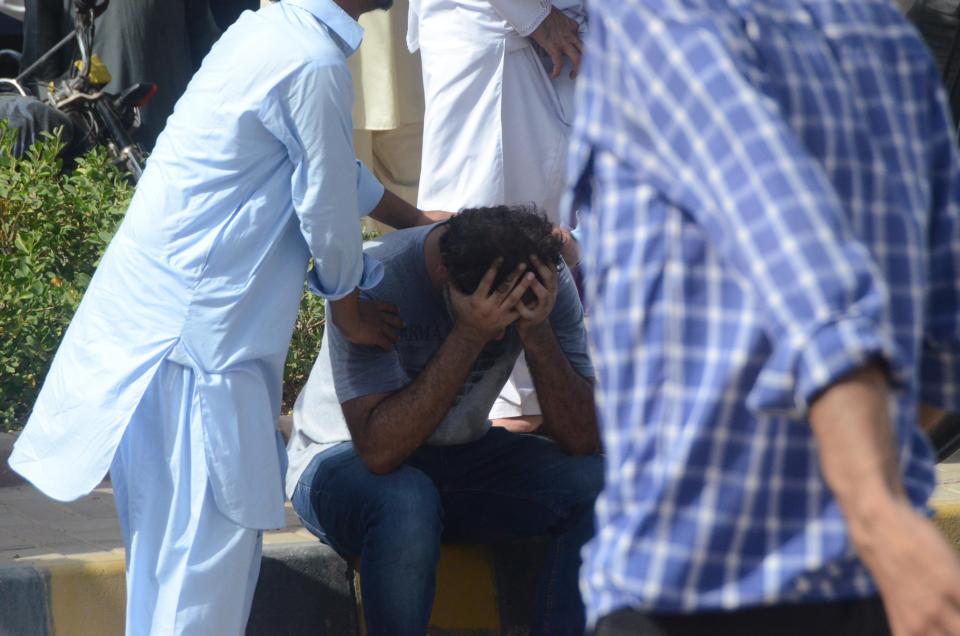 KARACHI, PAKISTAN, MAY 22: A weeping Pakistani man is being comfort at the site of a passenger plane crash in Karachi, Pakistan, May 22, 2020. A Pakistani passenger plane with at least 100 people on board crashed in a residential area in the Pakistani city of Karachi on Friday, the country's civil aviation agency said. (Photo by H.KHAN/Anadolu Agency via Getty Images)