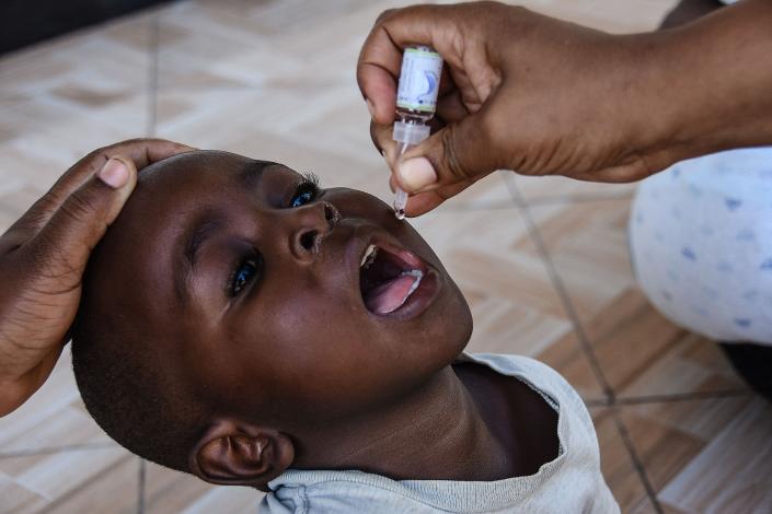A community health worker administers an oral polio vaccine during a door-to-door polio immunization campaign