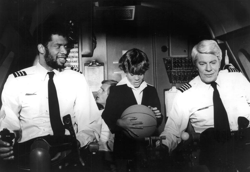 Kareem Abdul-Jabbar as co-pilot Roger Murdock (left) and Peter Graves as Captain Clarence Oveur show young Rossie Harris (Joey) how they check the controls in the 1980 Paramount Pictures' comedy spoof "Airplane!"