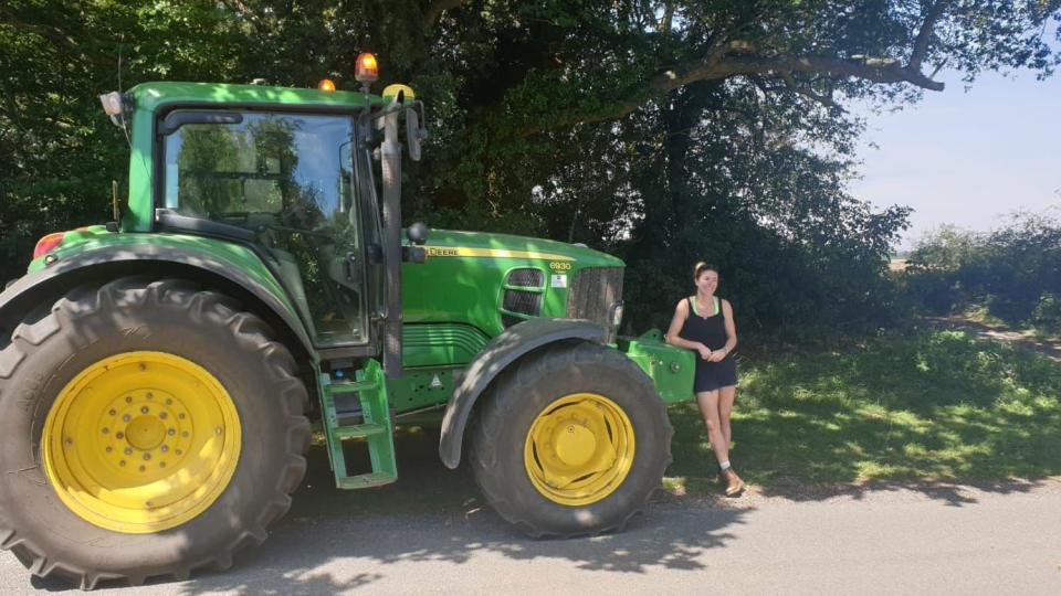 Georgina Langton McColl wearing a black playsuit and standing next to a green tractor