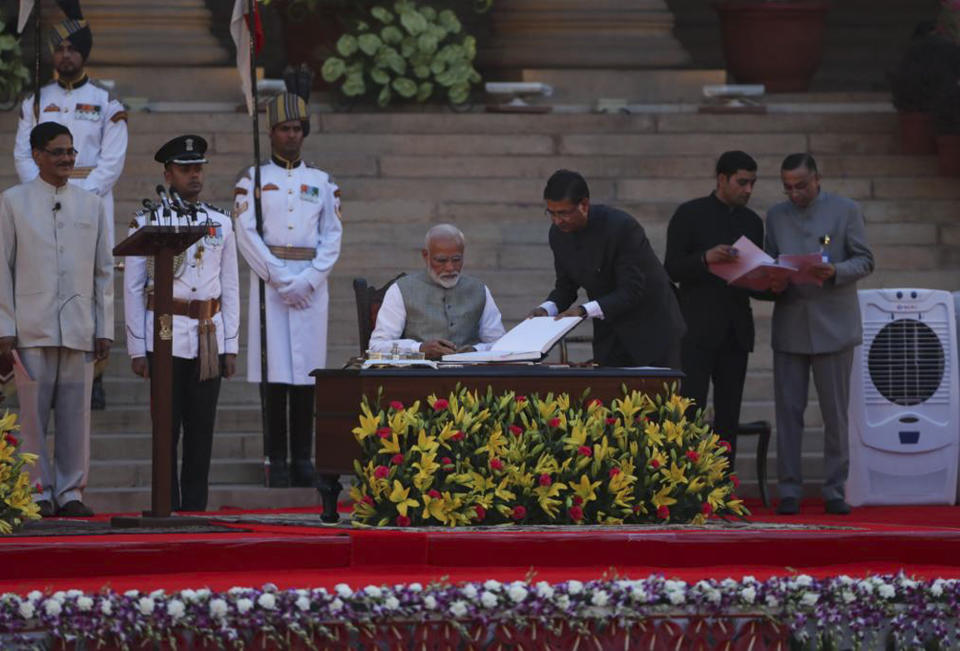 Narendra Modi, center, signs after taking oath for a second term as India's prime minister during a swearing in ceremony at the presidential palace in New Delhi, India, Thursday, May 30, 2019. Modi was sworn in Thursday for a second term after an overwhelming election victory for his Hindu nationalist party in a country of 1.3 billion people seeking swift economic change. (AP Photo/Manish Swarup)