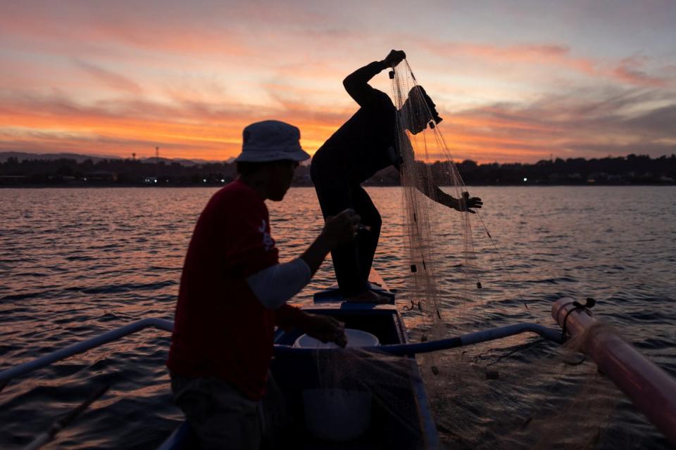 Jessie hauls his fishing net on his boat in Bacnotan, La Union (Reuters)