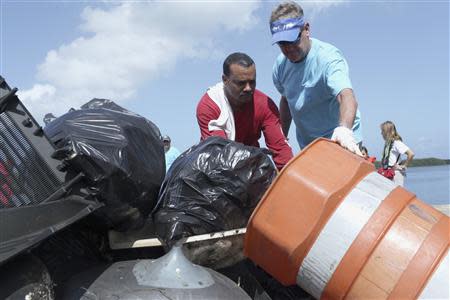 U.S. artist and conservationist Guy Harvey, (R), helps collect garbage as he leads a group of volunteers along the San Juan estuary system for the second "mega cleanup" of trash from the waterway, in San Juan October 26, 2013. REUTERS/Alvin Baez