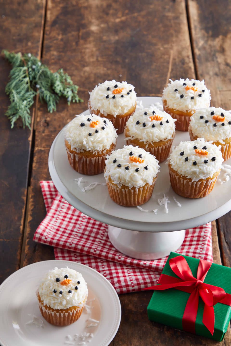 vanilla cupcakes topped with white frosting cocnut and decorated with a snowman face using icing