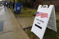 An information sign shows outside the Elk Grove Village Hall as voters wait in line during early voting at Elk Grove Village, Ill., Friday, Oct. 23, 2020. The US early voting total in 2020 has already exceeded the number of early votes cast in 2016 and there are still 11 more days to go until Election Day. (AP Photo/Nam Y. Huh)