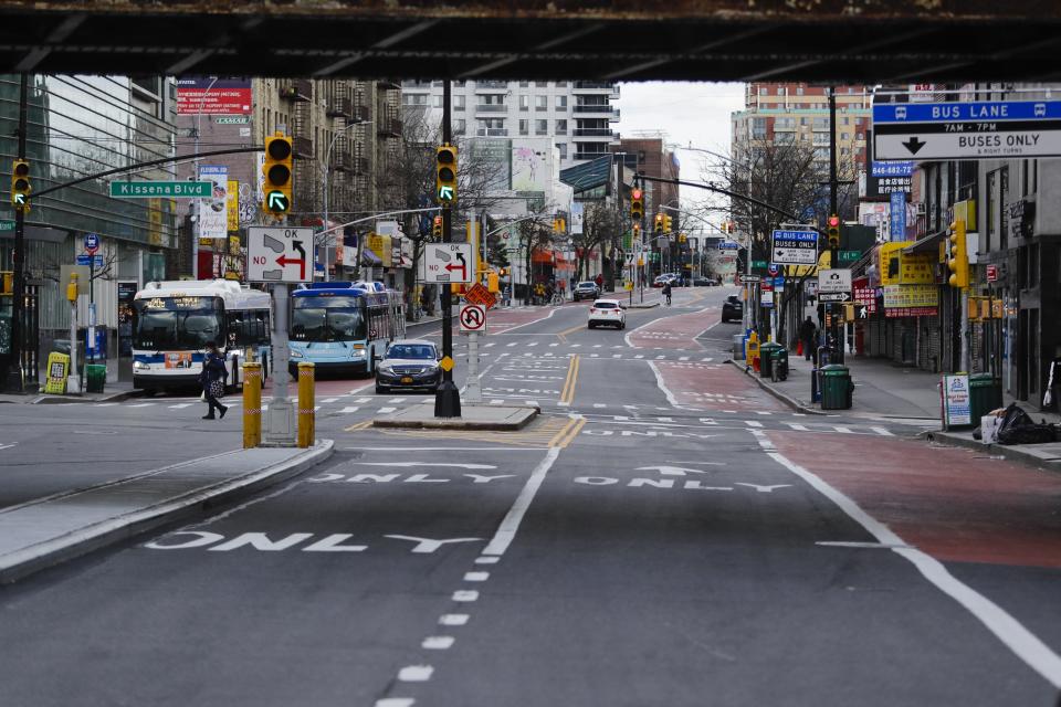 A pedestrian crosses Main Street near Kissena Boulevard Wednesday, April 1, 2020, in the Flushing section of the Queens borough of New York. The new coronavirus causes mild or moderate symptoms for most people, but for some, especially older adults and people with existing health problems, it can cause more severe illness or death. (AP Photo/Frank Franklin II)