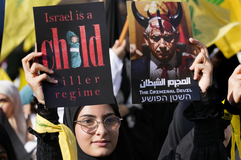 A supporter of the Iranian-backed Hezbollah group hold posters against the Israeli Prime Minister Benjamin Netanyahu, as she waits the speech of Hezbollah leader Sayyed Hassan Nasrallah during a rally to commemorate Hezbollah fighters who were killed in South Lebanon last few weeks while fighting against the Israeli forces, in Beirut, Lebanon, Friday, Nov. 3, 2023. Nasrallah's speech had been widely anticipated throughout the region as a sign of whether the Israel-Hamas conflict would spiral into a regional war. (AP Photo/Hussein Malla)