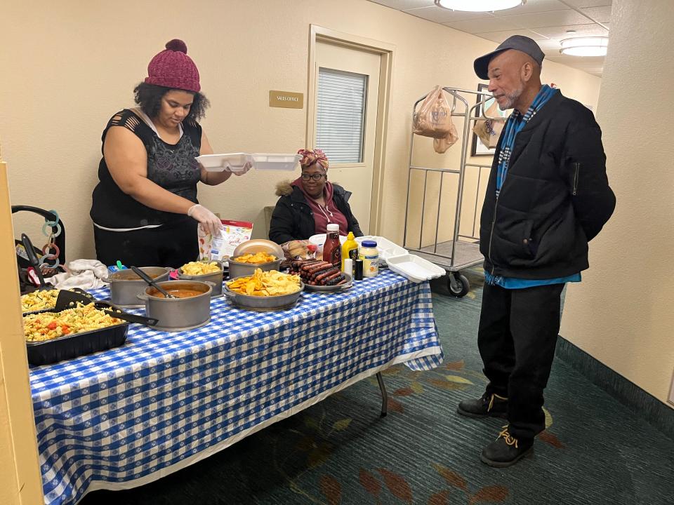 Daisha Harper, left, serves food she made into a to-go container for Rodrigues Hammond, right, while Audriana Watson looks on. All three are former residents of Latitude Five25 and were staying in an area motel in February after being evacuated from their apartments on Christmas Day.