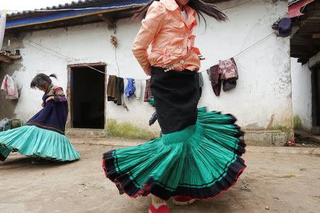 A Yi ethnic minority girl Jisi Mewuzuo (R) and her sister Jisi Meyouzuo dance holding traditional Yi skirts in Butuo County, Sichuan province, China July 19, 2017. REUTERS/Natalie Thomas