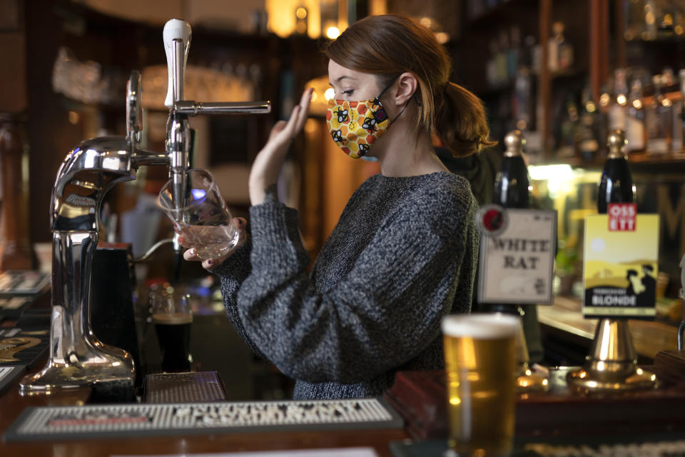 A member of staff pours a drink, at the Dispensary pub in Liverpool, England, Monday Oct 12, 2020. The British government has carved England into three tiers of risk in a bid to slow the spread of a resurgent coronavirus. The northern city of Liverpool is in the highest category and will close pubs, gyms and betting shops. (AP Photo/Jon Super)