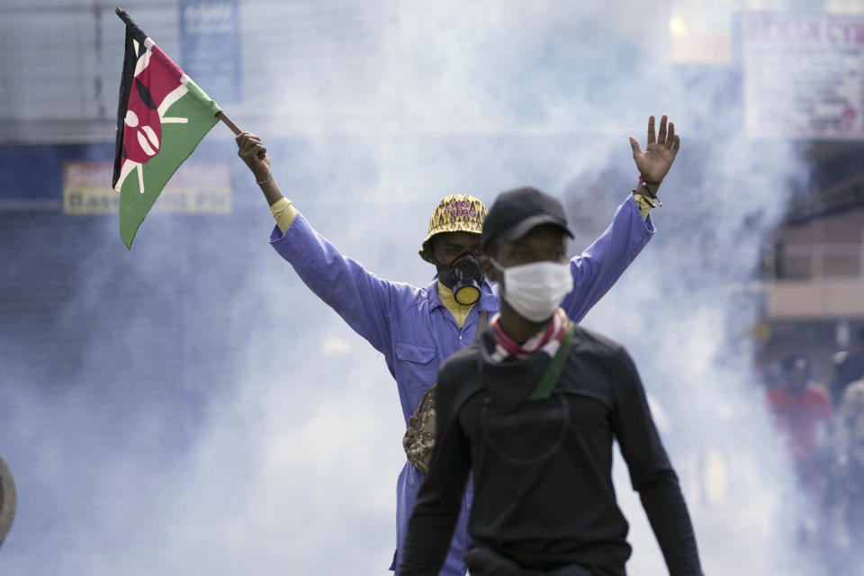 Un manifestante antigubernamental ondea una bandera de Kenia mientras la policía dispara gases lacrimógenos durante una propuesta contra una propuesta de subida de impuestos en el centro de Nairobi, Kenia, el 25 de junio de 2024. (AP Foto/Brian Inganga)