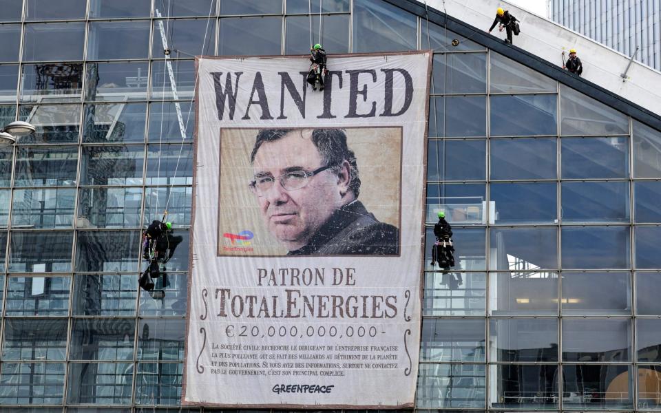 Environmental activists from Greenpeace display a banner bearing the portrait of TotalEnergies Chief Executive Officer (CEO) Patrick Pouyanne