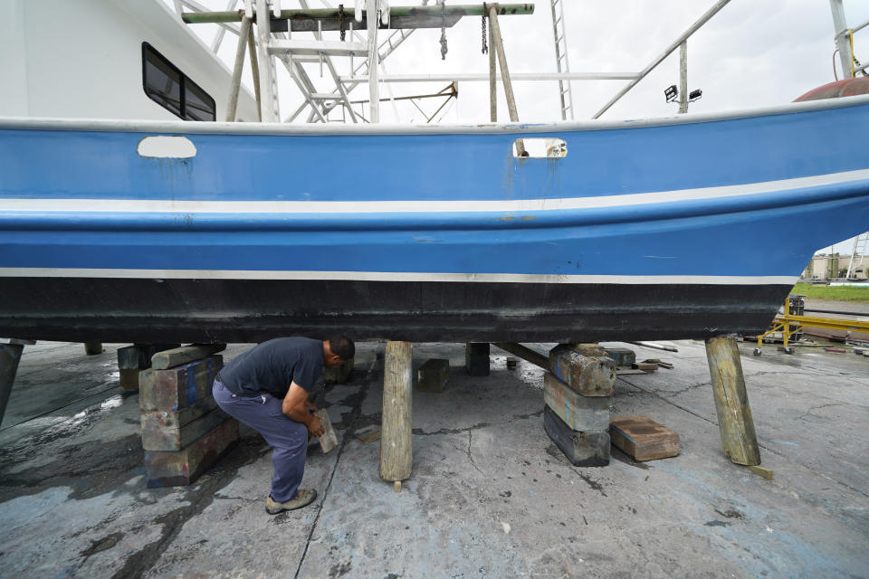 Mike Bartholemey places extra blocks under his recently dry docked shrimp boat, out of concern for strong winds, in Empire, La., Sunday, Aug. 23, 2020, in advance of Hurricane Marco, expected to make landfall on the Southern Louisiana coast. (AP Photo/Gerald Herbert)